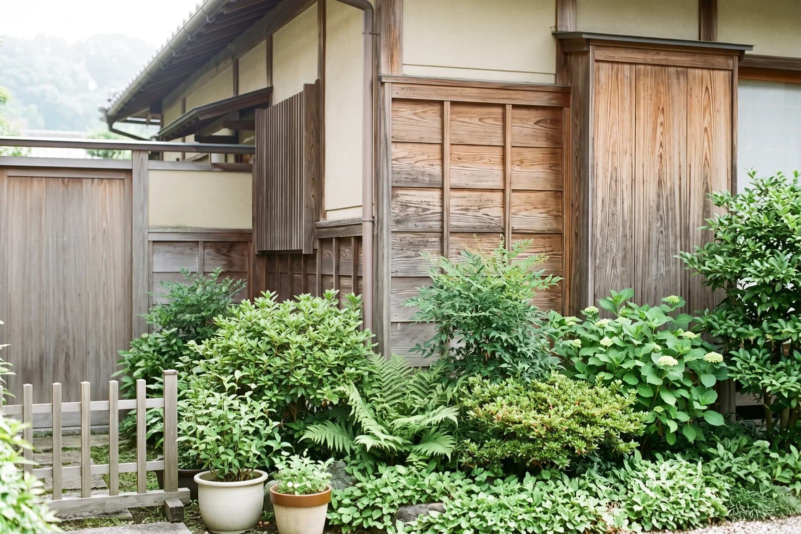 木造住宅の外壁と、手入れされた庭の植え込みの様子