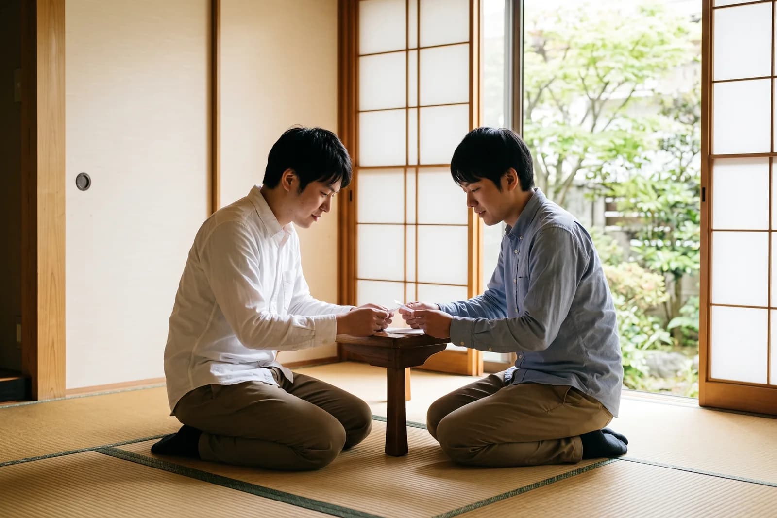 和室の畳の上で、兄弟が並んで座りながら手元に視線を落としている様子