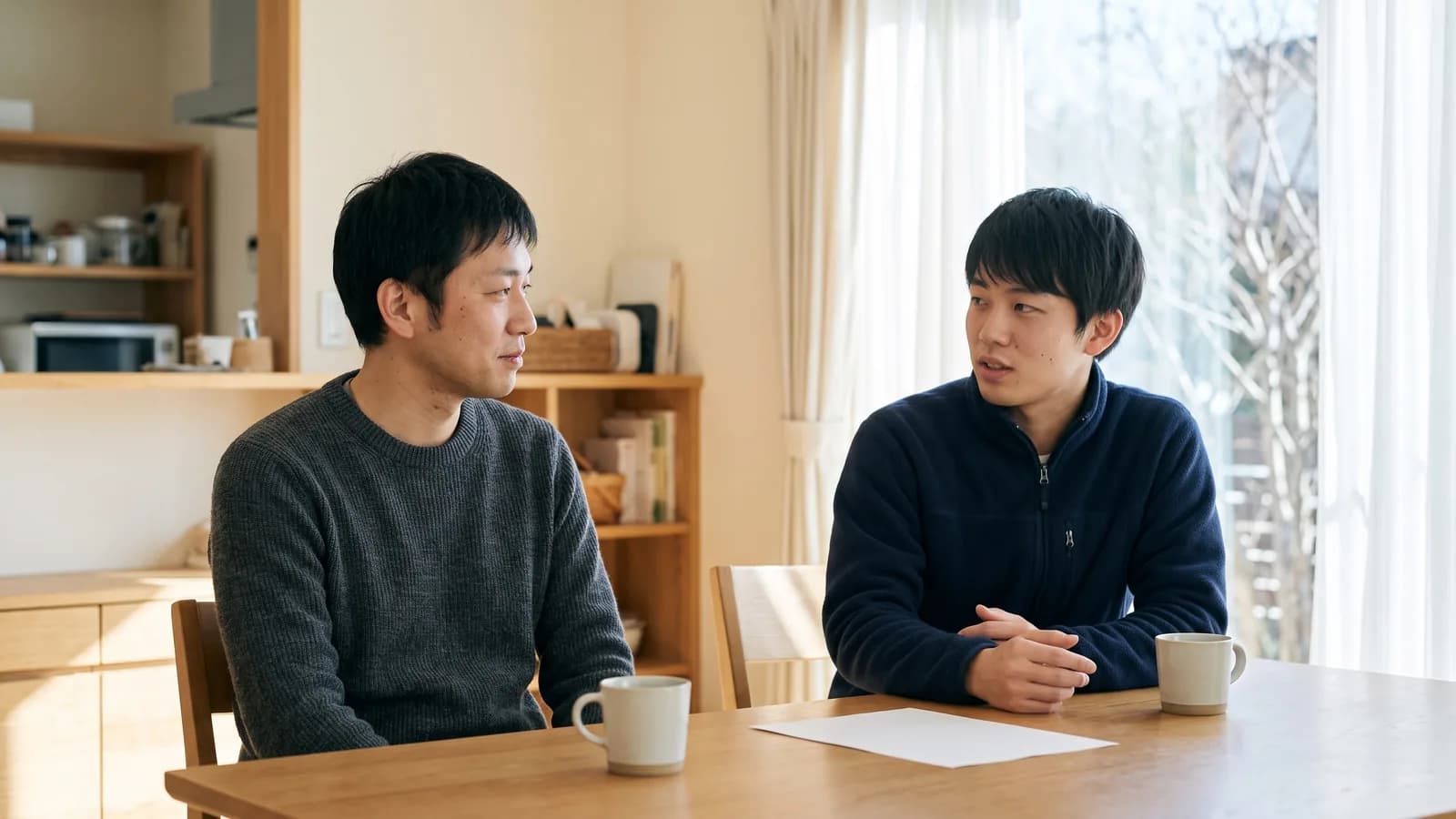 リビングのテーブルで、兄弟が並んで座り、うなずきながら話し合っている様子